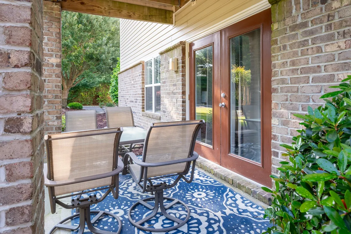 A welcoming outdoor seating area is depicted, with a stylish decorative rug, double glass doors, and cozy furniture. The space is ground-level and easily accessible, ideal for unwinding with pets after an active day outside.