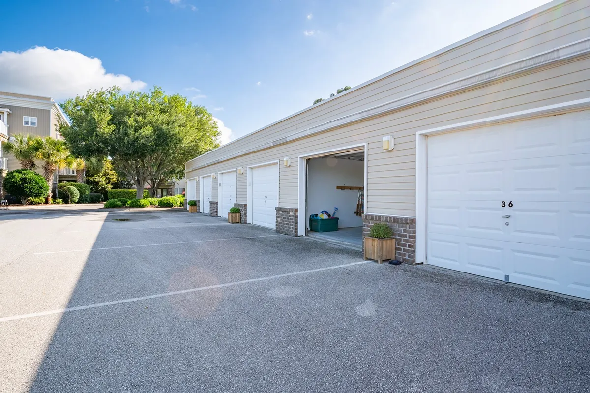 An exterior view of the building’s garage doors, framed by planters and mature trees, conveying organized access and the presence of private garage facilities. The setting feels calm and secure.
