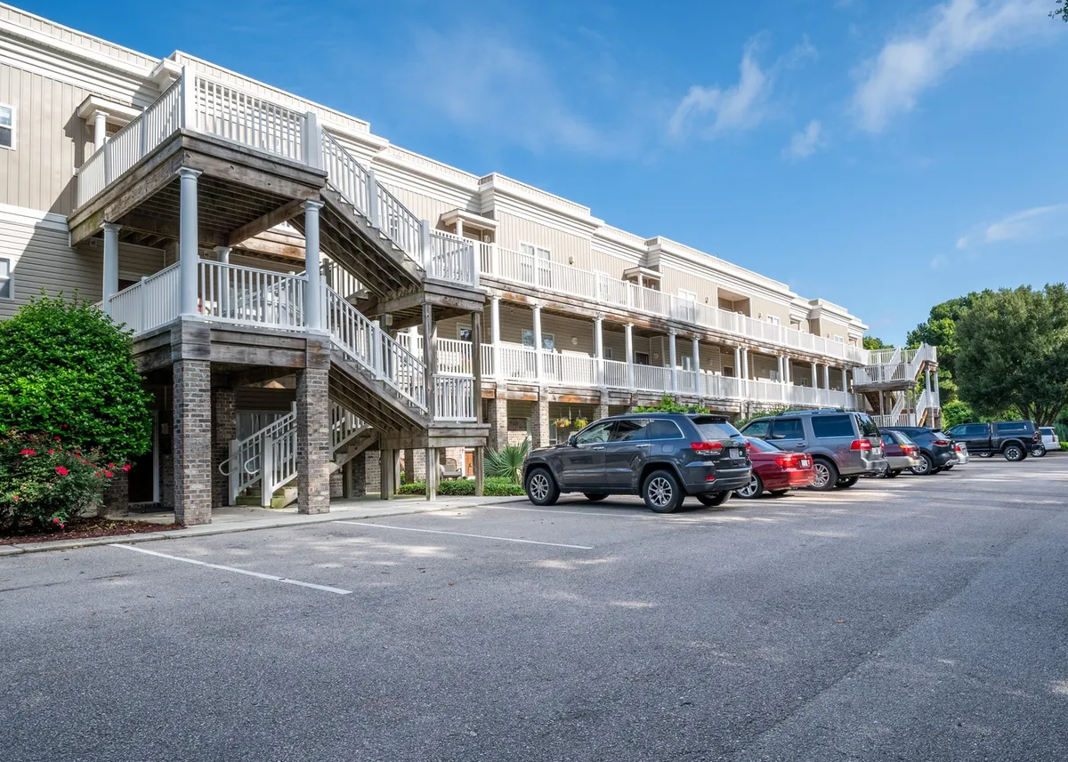 An inviting exterior scene featuring a staircase, parking area, and lush green landscaping. The space is ideal for casual outdoor get-togethers, morning coffee on the balcony, or convenient comings and goings for group excursions to local restaurants and attractions.