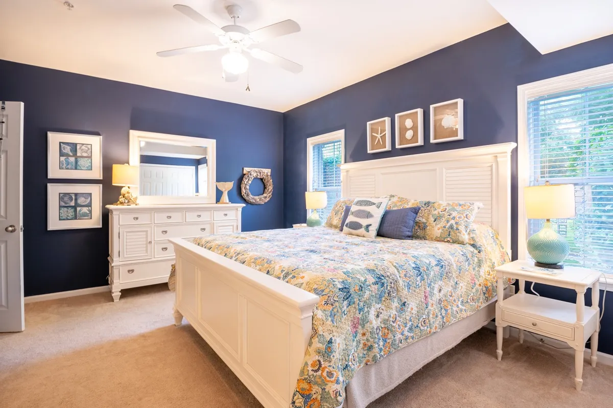 A cozy and serene bedroom featuring a comfortable bed with soft linens, matching nightstands, decorative wall art, and a dresser. Natural light filters gently into the room, creating an inviting retreat for rest and relaxation.